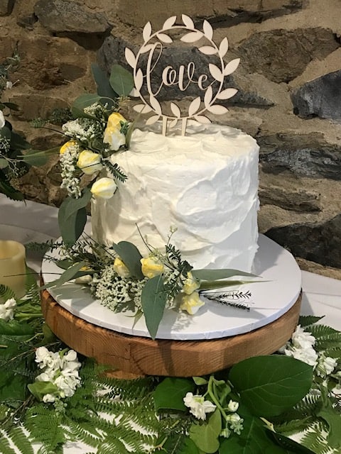 A wedding cake decorated with flowers and eucalyptus leaves.