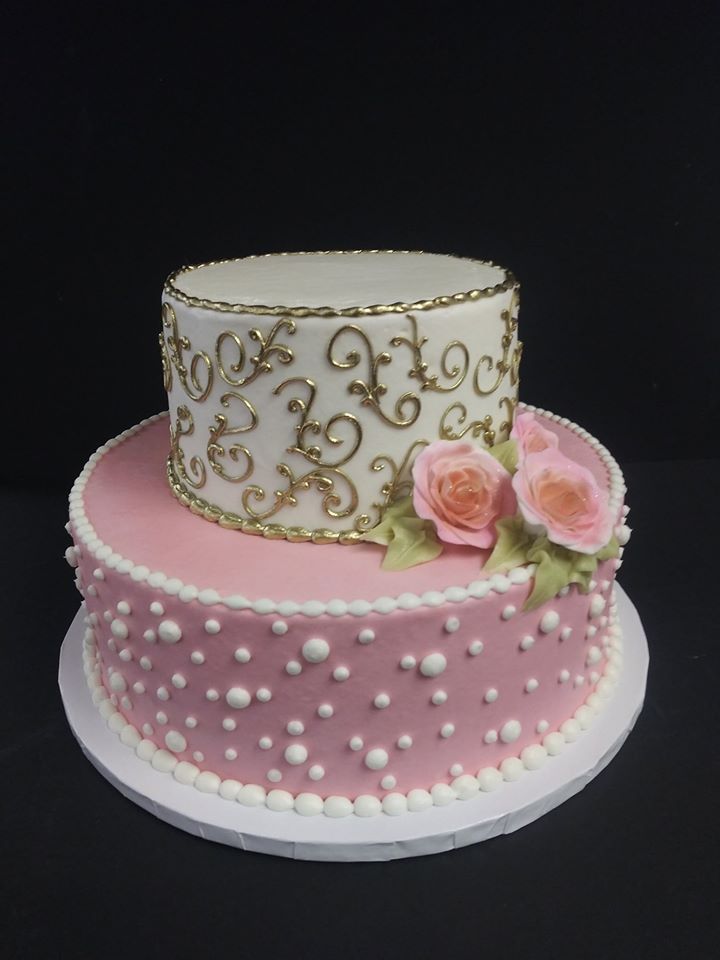 A pink and gold cake decorated with roses.