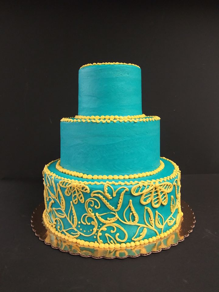 A blue and yellow wedding cake on a black background.