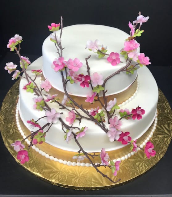 A white cake with pink blossoms on top.