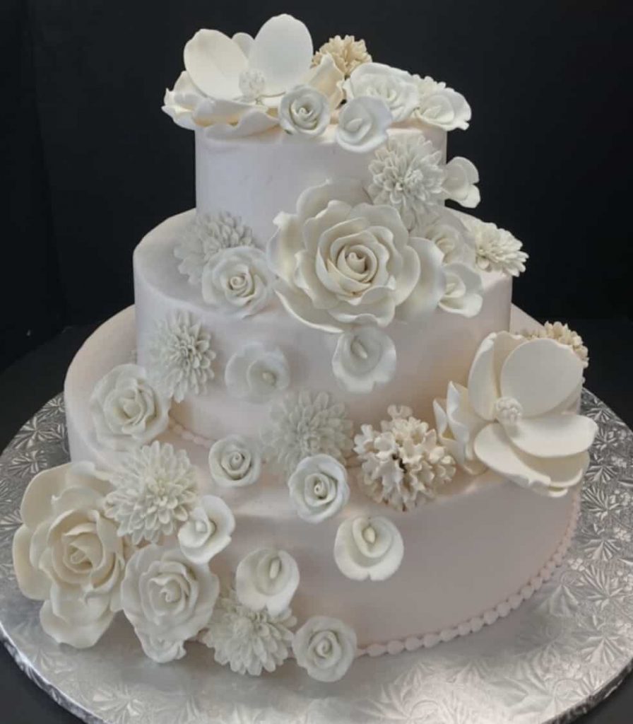 A white wedding cake decorated with white flowers.