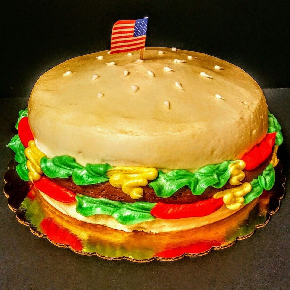 A burger cake with an american flag on top.