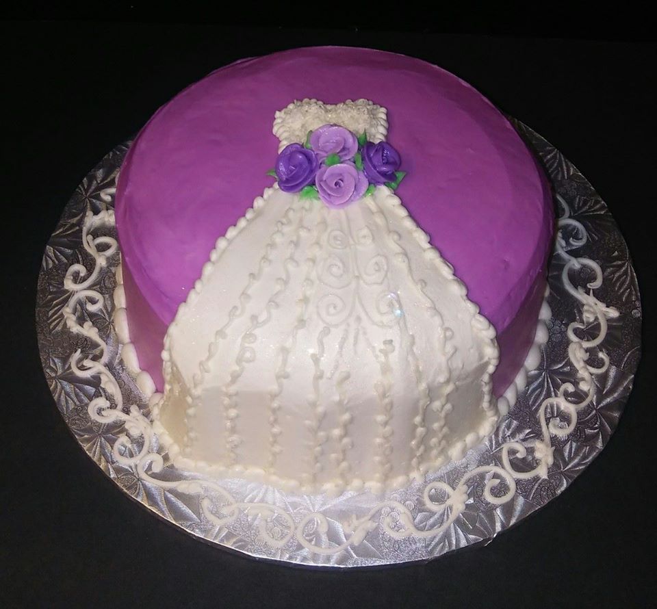 A wedding cake with a purple dress on top.