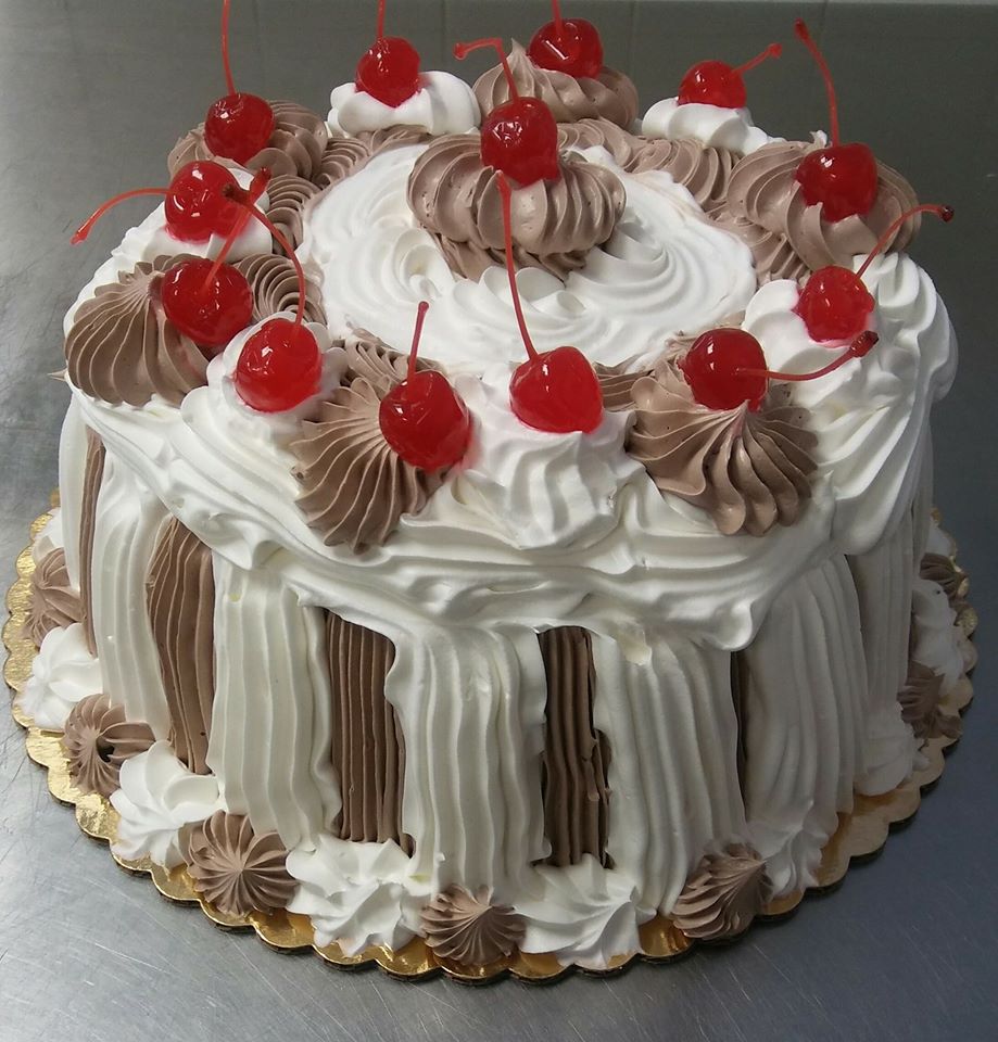 A white and chocolate cake with cherries on top.