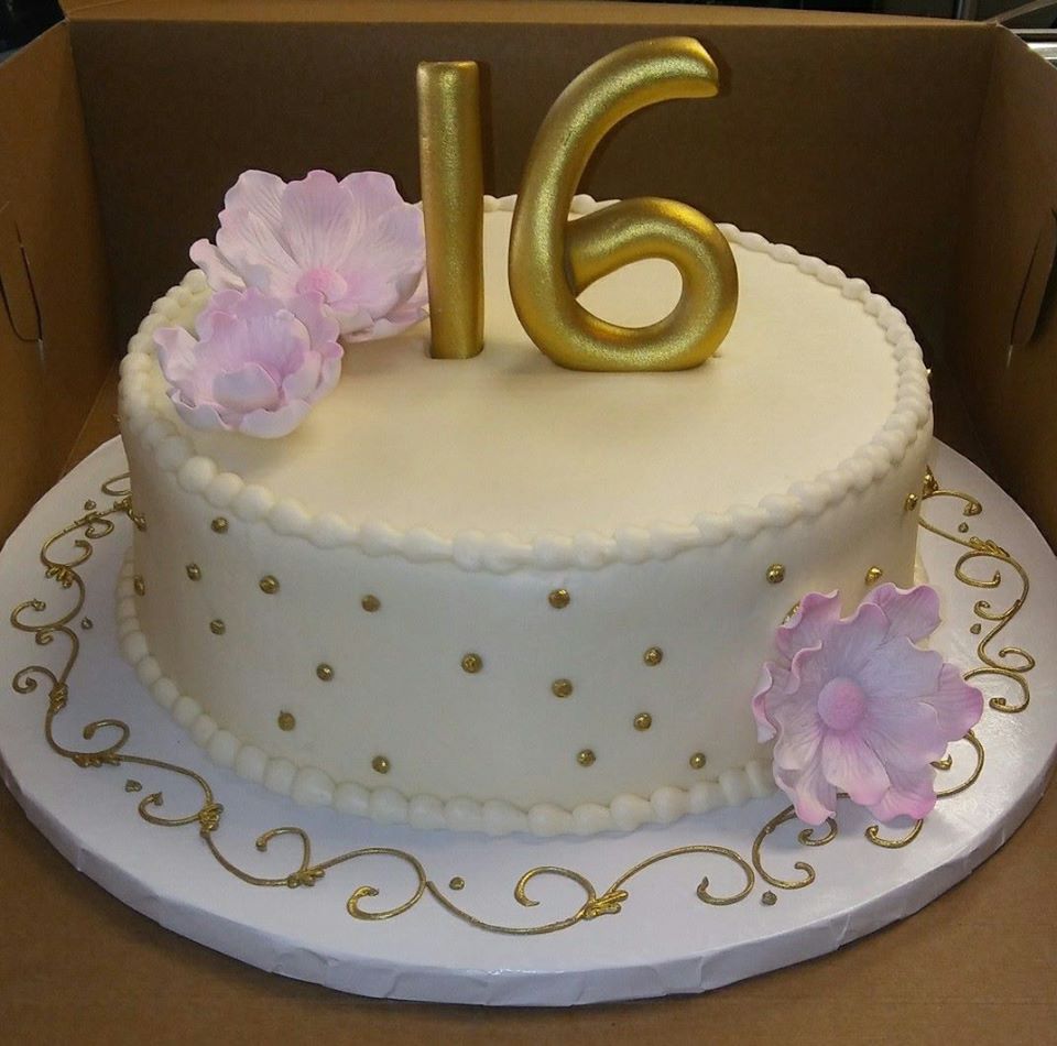 A 16th birthday cake decorated with gold and pink flowers.