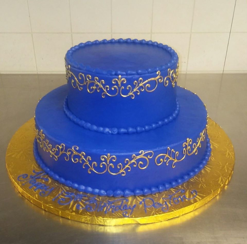 A blue cake with gold decorations on top.
