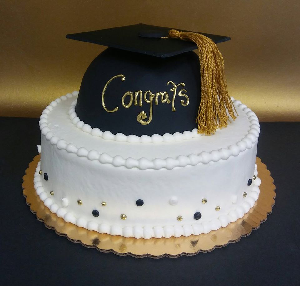 A black and gold graduation cake with a tassel on top.