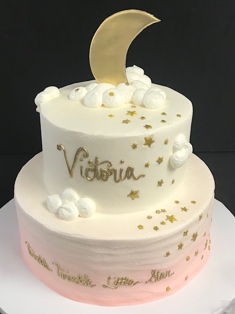 A pink and gold cake with the name victoria.