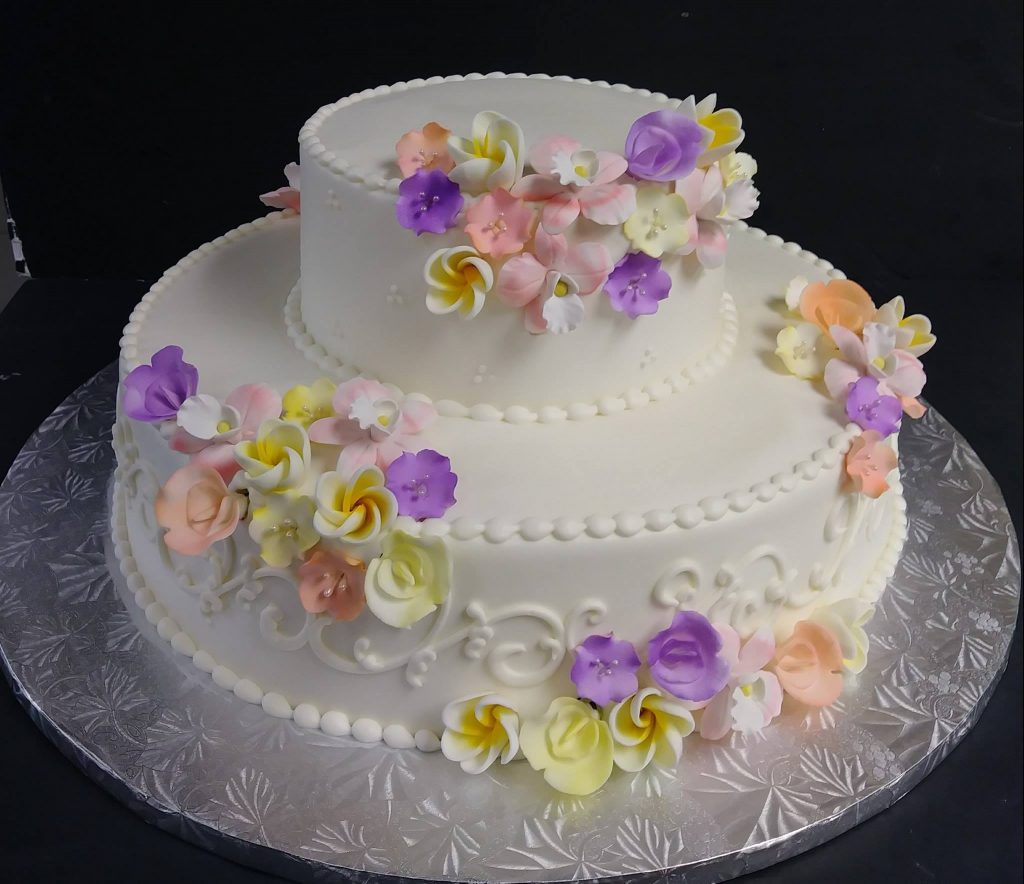 A white cake decorated with purple and yellow flowers.
