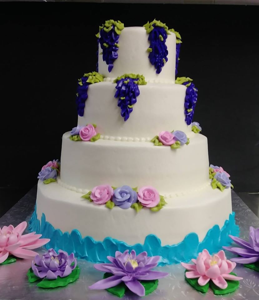 A three tier cake decorated with purple flowers and lilies.