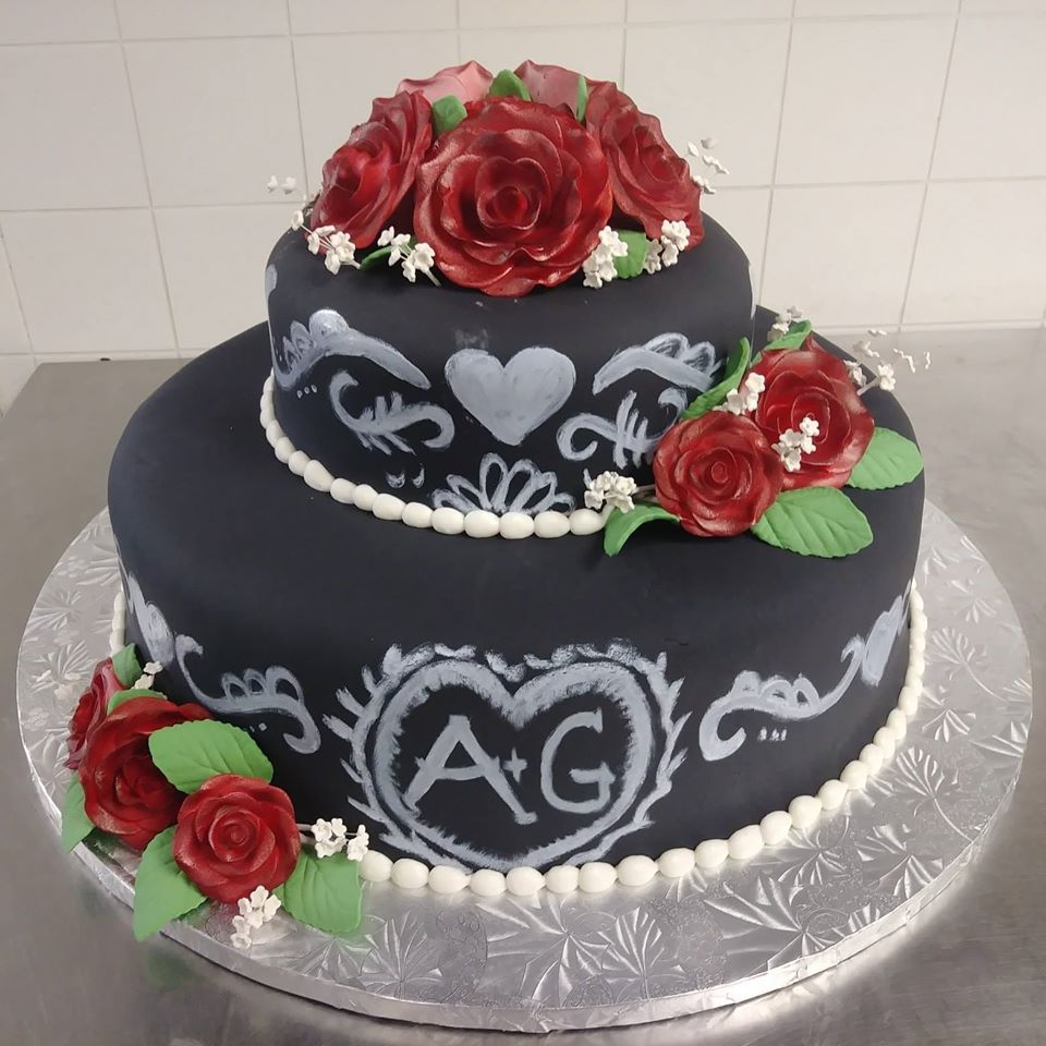 A black cake decorated with roses and a heart.