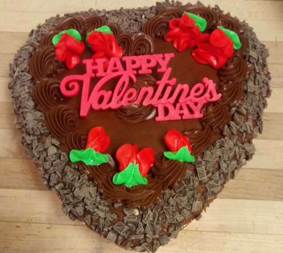 A chocolate heart shaped cake with a happy valentine's day message.