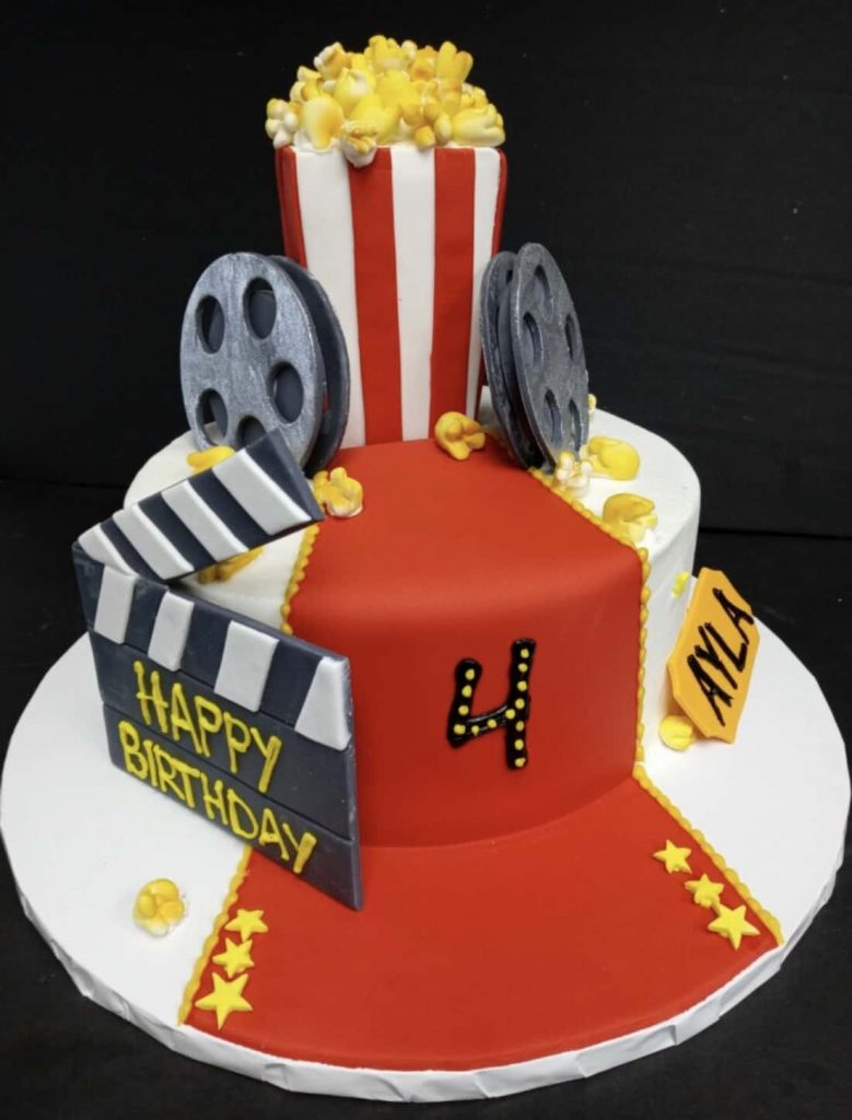 A birthday cake decorated with movie claps and popcorn.