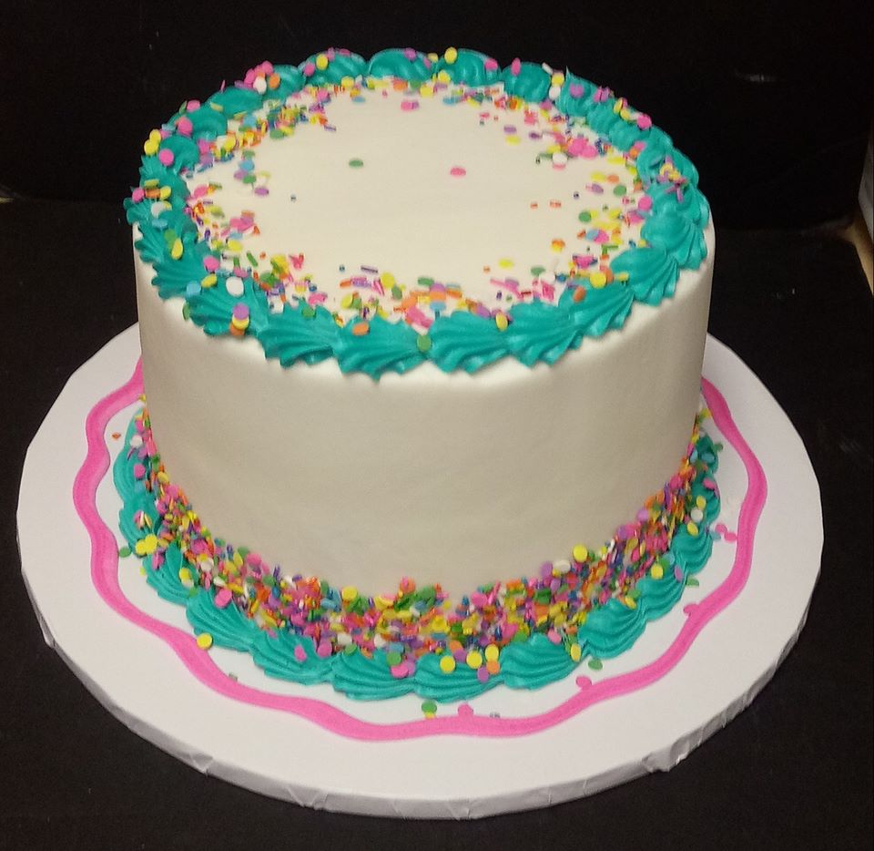 A white cake with blue and pink sprinkles on top.