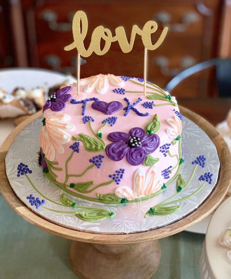 A pink and purple cake with the word love on top.