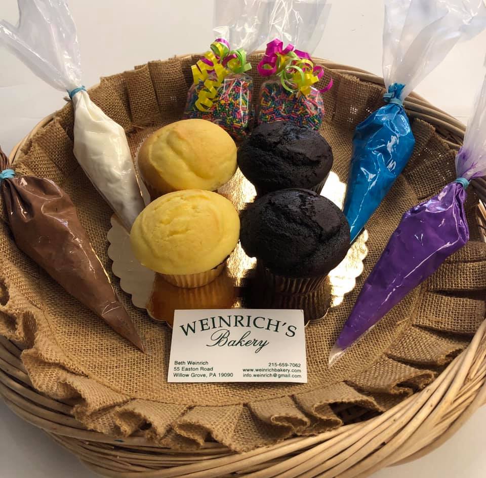 A basket filled with cupcakes, cookies and candy.
