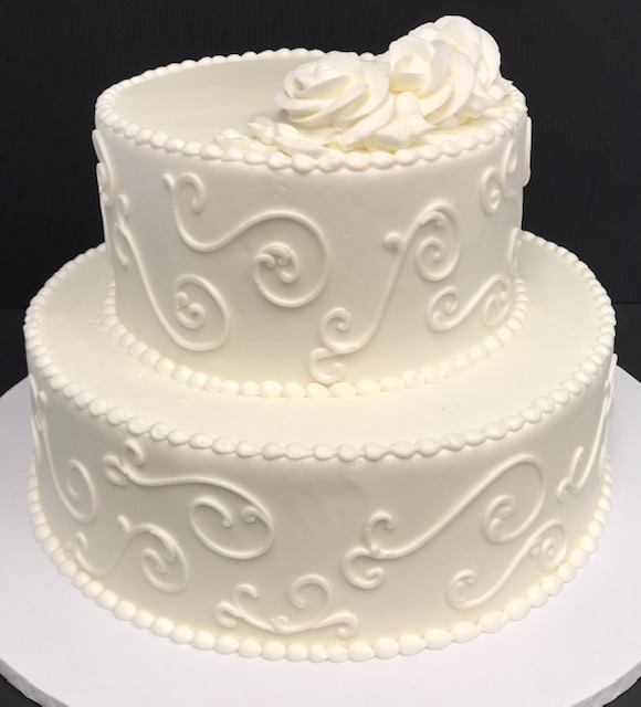 A white cake decorated with swirls and flowers.